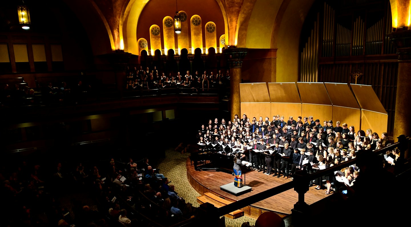 Koor treedt op in een grote concertzaal.