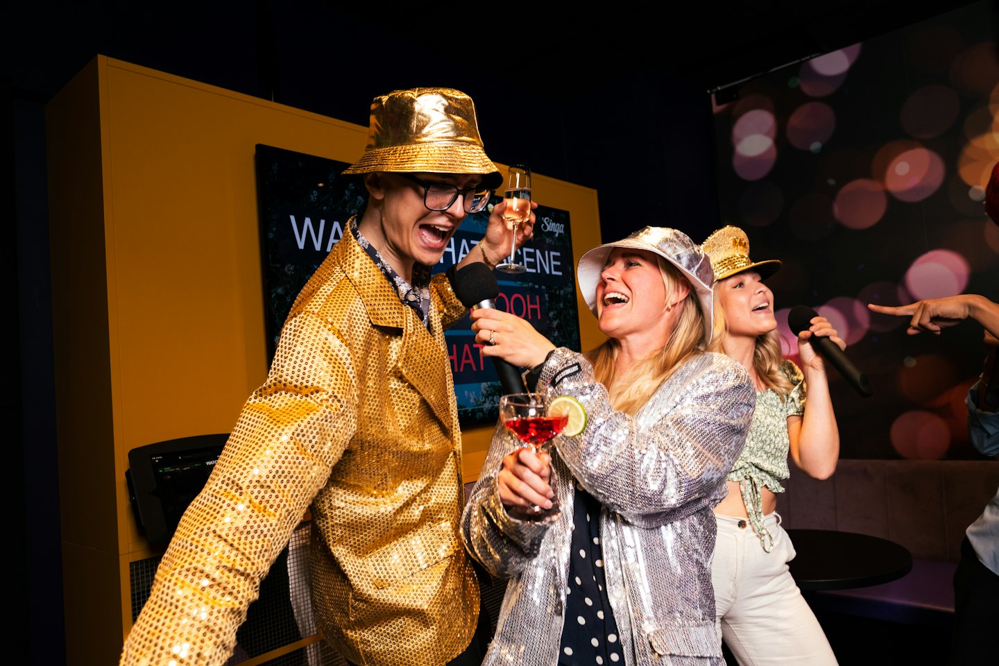 Vrienden die karaoke zingen in feestelijke kleding met drankjes.
